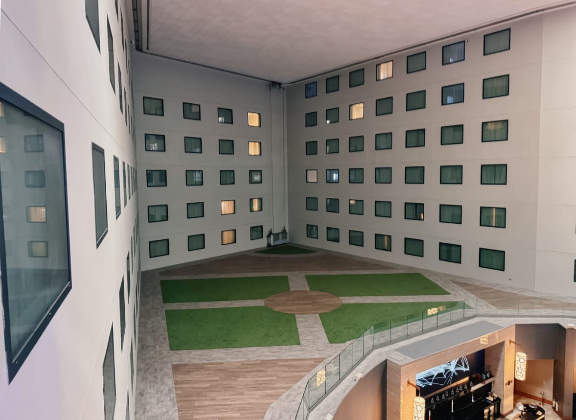 A roofed interior courtyard area in a hotel, with windows looking out over a gloomy empty unused space