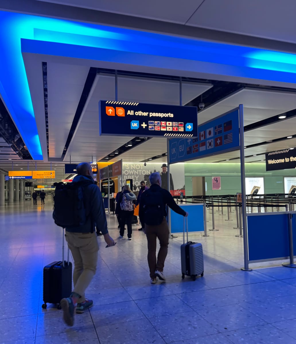 The arrivals / customs area at Heathrow Terminal 2, with blue lighting and large empty areas in the background.