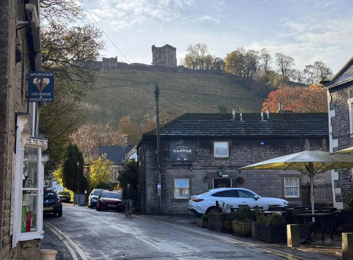 A charming street in Castleton, with a castle on the hill above