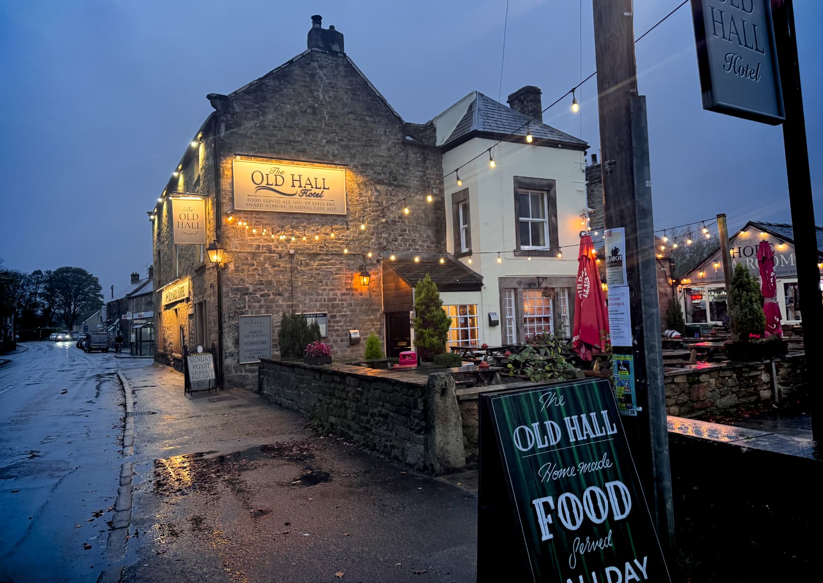 The Old Hall Hotel in Hope, UK, in a rainy dusk with warm lights inside