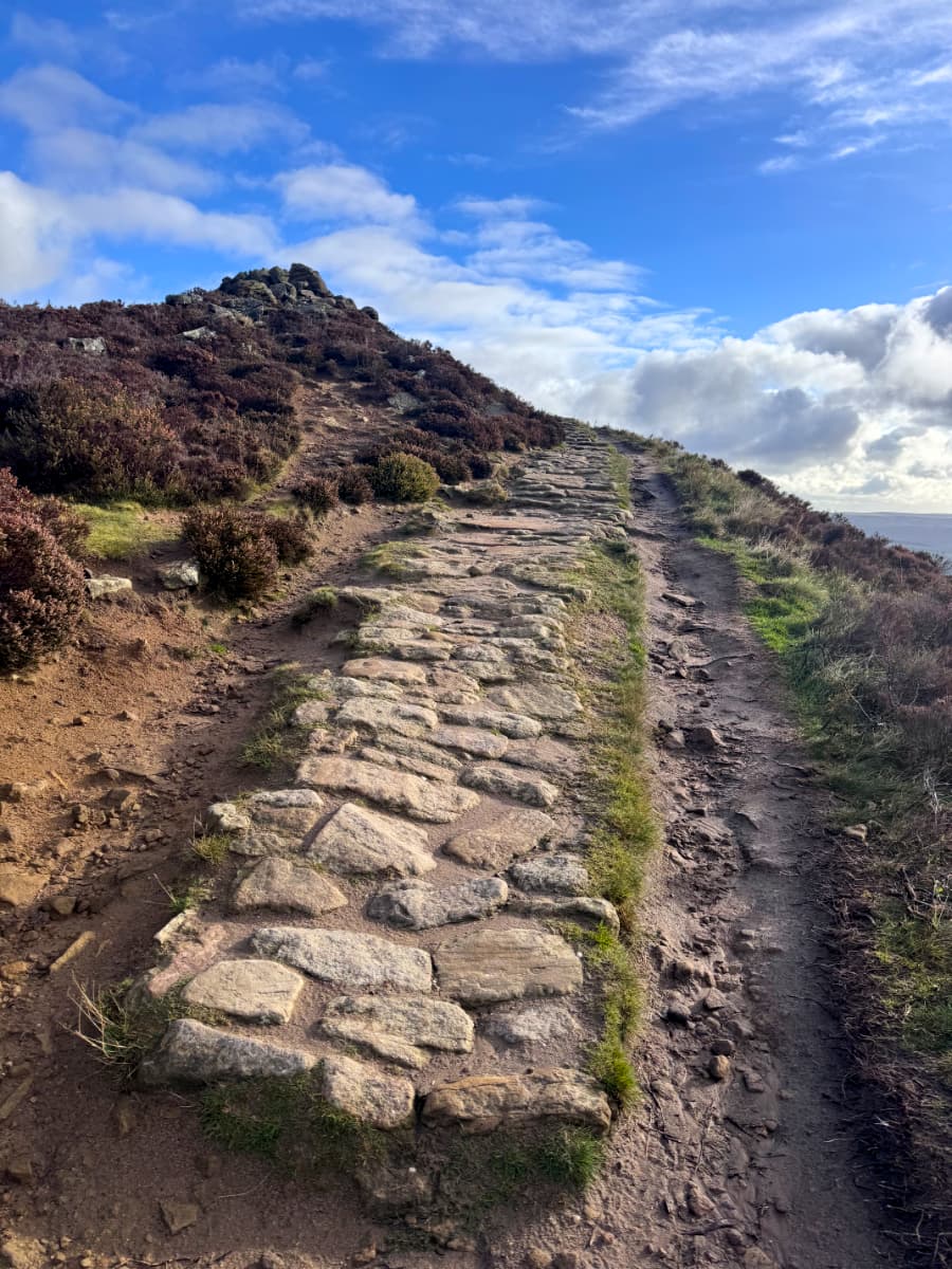 A stone road winding along the side of Win Hill Pike