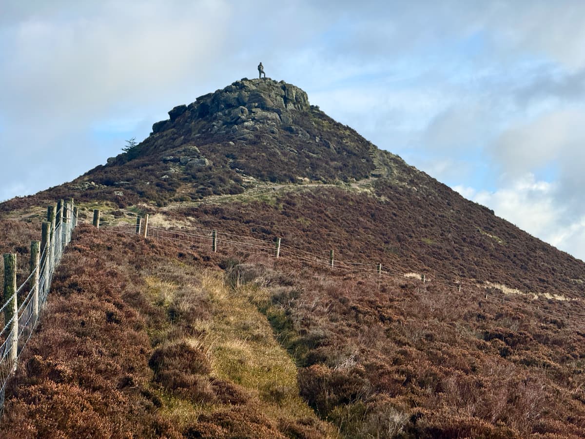A rocky hilltop with a figure standing atop it